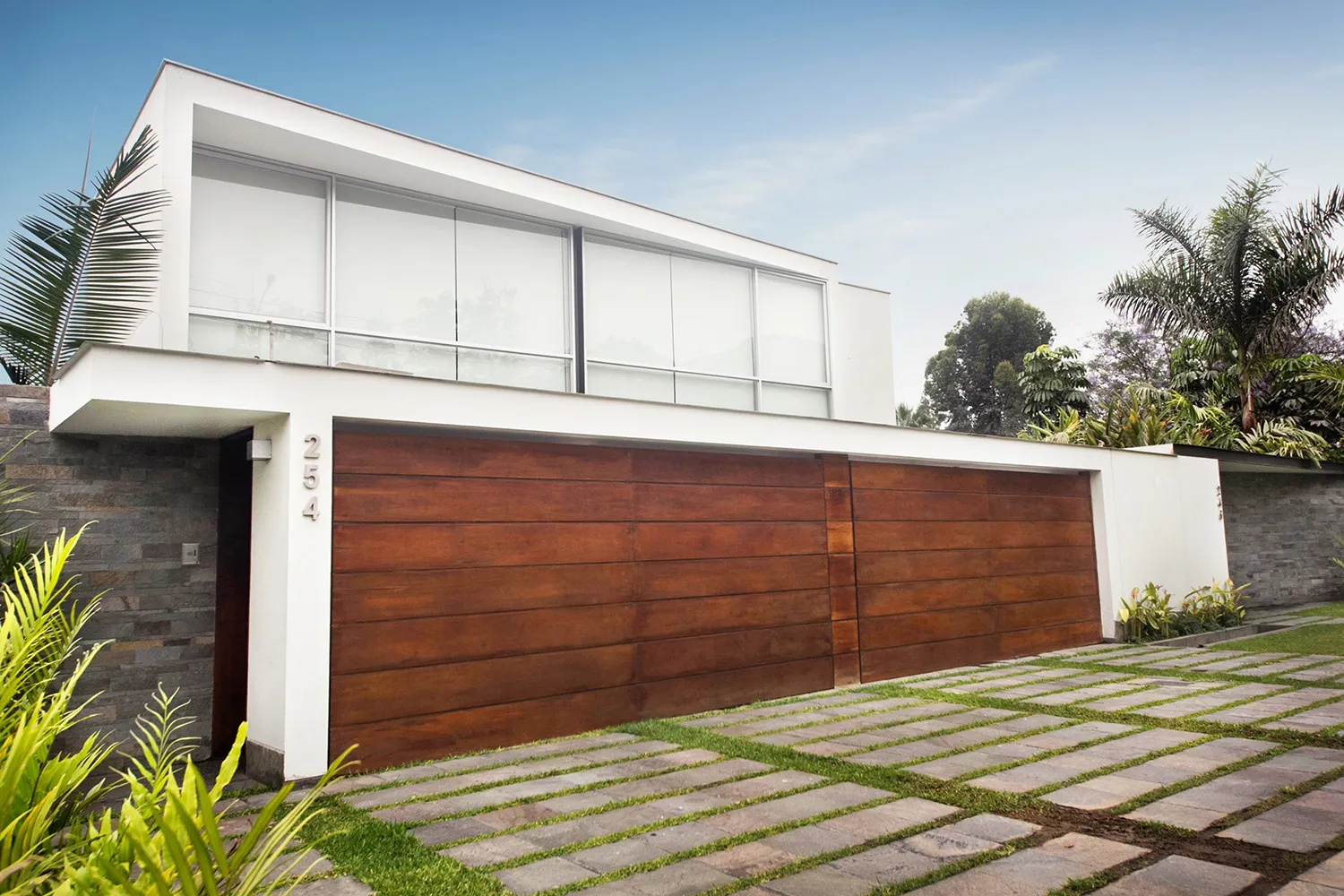 Fachada blanca de la Casa Salem con portón de madera y jardín delantero.